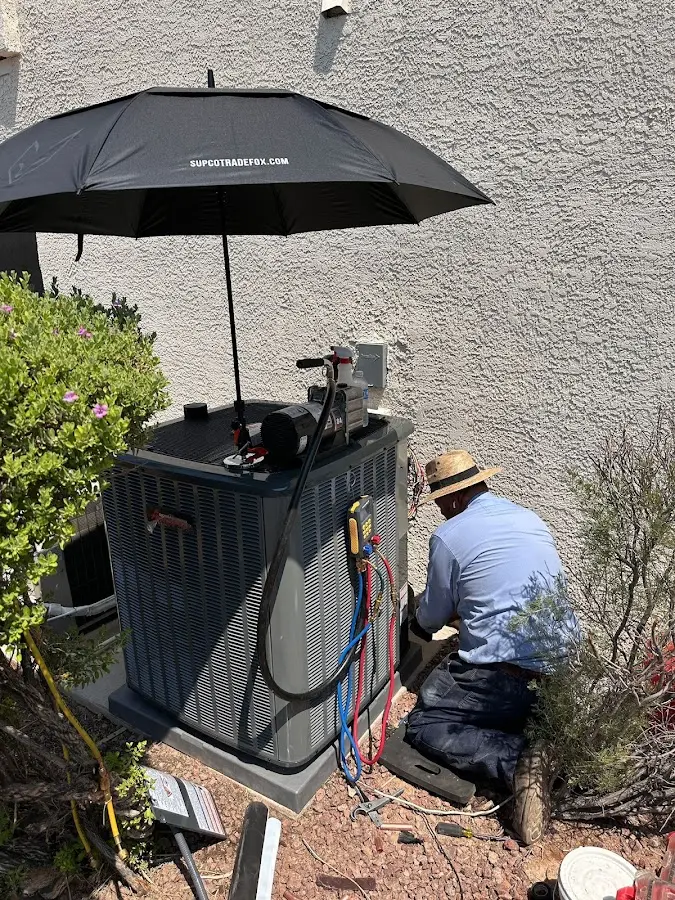 HVAC technician performing outdoor AC maintenance in Indianola